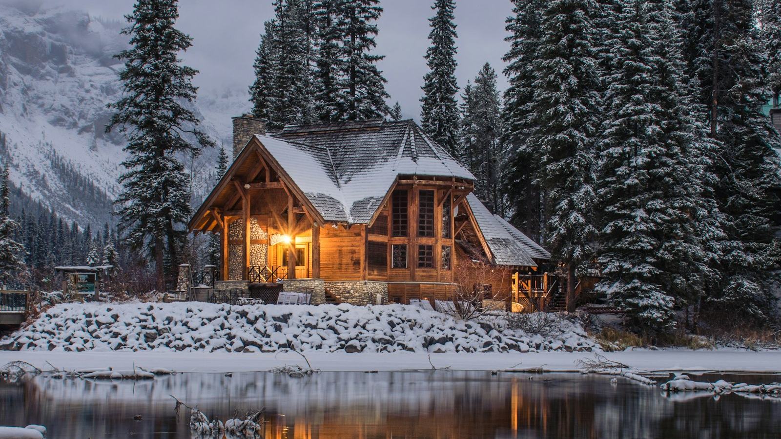 Warmly lit timber home on a frozen lake at dusk — winter readiness is local, and so is FrostList