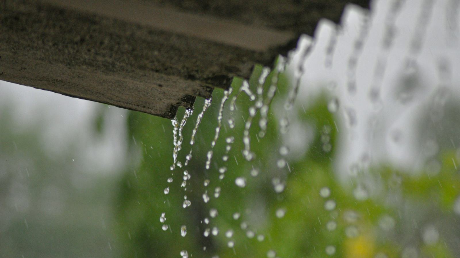 Meltwater and rain streaming off a roof edge — spring thaw is when a working sump pump earns its keep